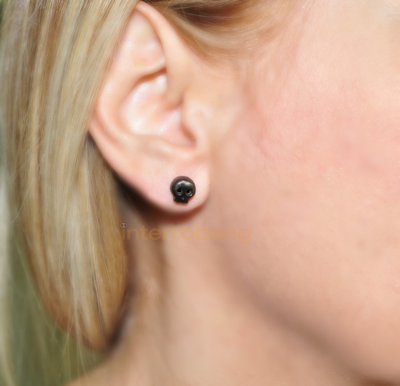 May include: A pair of black skull stud earrings. The earrings are small and simple, and they are a great way to add a touch of edgy style to any outfit.