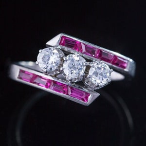 May include: A silver ring with three round diamonds and three pink rectangular stones set in a curved band.