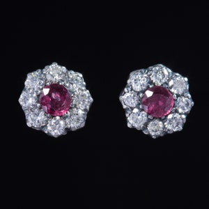 Puede incluir: Un par de pendientes de plata con una piedra preciosa de rubí rojo rodeada por un halo de piedras blancas más pequeñas.