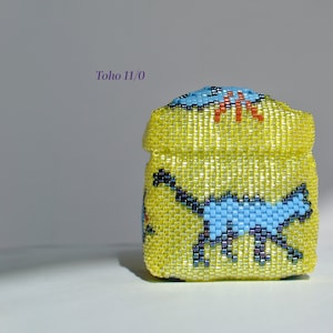 May include: A small, yellow beaded box with a blue and black cat design. The box is made with Toho 11/0 beads.