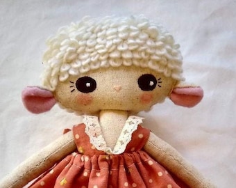May include: A handmade doll with a white curly wig, pink ears, and a red dress with white polka dots. The doll has a sweet, innocent expression.