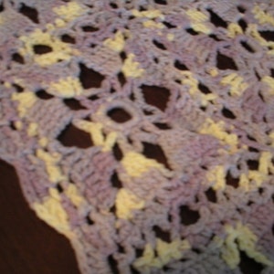 May include: A crocheted throw blanket with a delicate pattern in shades of purple and yellow.