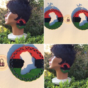 Puede incluir: Un par de pendientes grandes y redondos con una silueta de rostro de mujer recortada. Los pendientes están pintados en rojo, negro y verde, con un borde de encaje verde. Los pendientes se muestran en un maniquí con cabello negro corto.