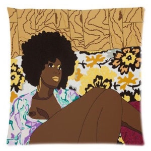 Puede incluir: Una mujer con un peinado afro est&aacute; tumbada en un sof&aacute; con estampado floral. Lleva una camisa con estampado morado y verde y pendientes de oro. El fondo es un patr&oacute;n de madera marr&oacute;n.