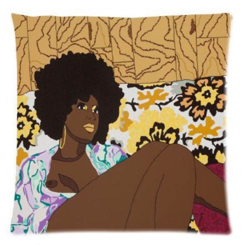 Puede incluir: Una mujer con un peinado afro est&aacute; tumbada en un sof&aacute; con estampado floral. Lleva una camisa con estampado morado y verde y pendientes de oro. El fondo es un patr&oacute;n de madera marr&oacute;n.