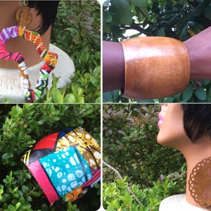 Könnte beinhalten: Ein Set an afrikanisch inspiriertem Schmuck und Accessoires, darunter ein Holz-Armreif, ein Paar Holz-Ohrringe in Form des afrikanischen Kontinents und eine Halskette aus buntem Stoff. Der Schmuck wird auf einer Puppe und vor einem Hintergrund aus grünem Laub präsentiert.