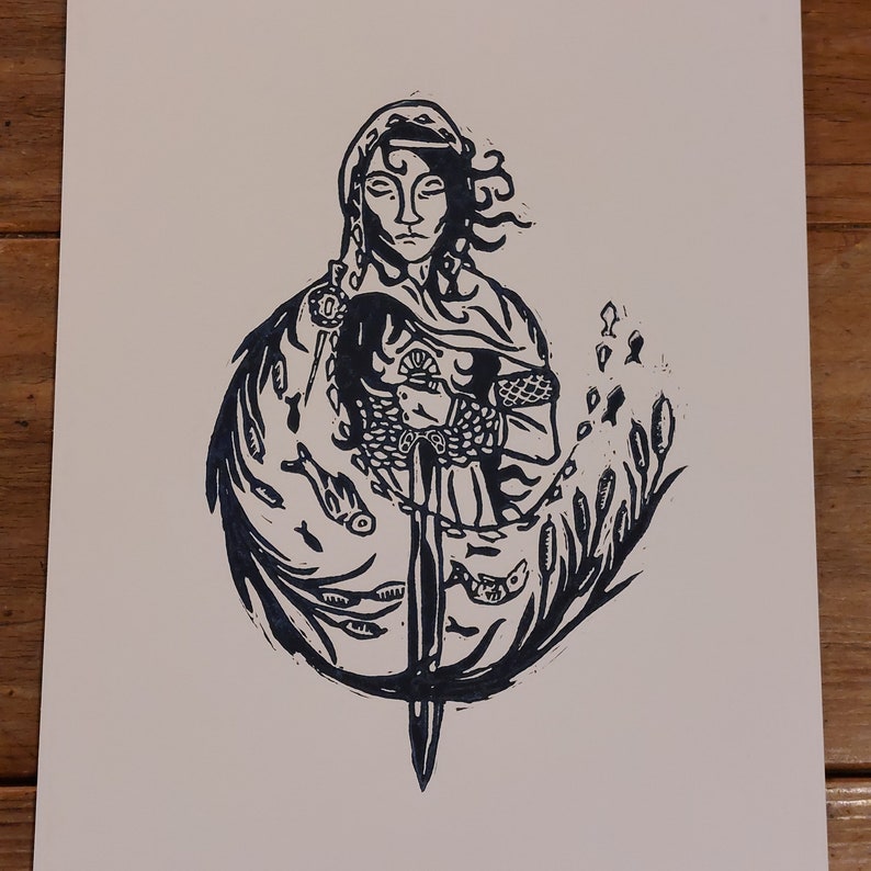 May include: Black and white woodcut print of a woman holding a sword. She is surrounded by stylised fish and reeds. The woman is wearing a hooded cloak and chainmail.