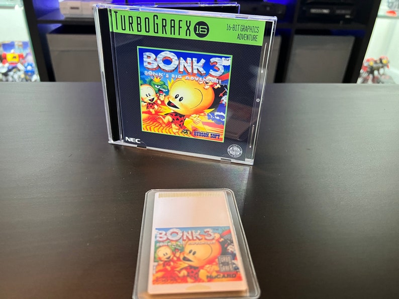 May include: A TurboGrafx-16 game case for Bonk 3, featuring a cartoon character on the cover. The game case is in a clear plastic case. A HuCard game cartridge for Bonk 3 is in a clear plastic case.