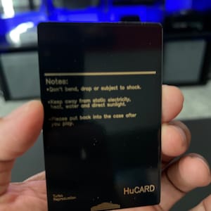 May include: A black HuCARD with gold text. The card has the text "Notes: Don't bend, drop or subject to shock. Keep away from static electricity, heat, water and direct sunlight. Please put back into the case after you play." The bottom of the card reads "Turbo Reproduction."