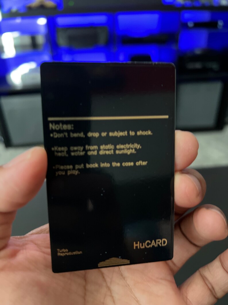 May include: A black HuCARD with gold text. The card has the text "Notes: Don't bend, drop or subject to shock. Keep away from static electricity, heat, water and direct sunlight. Please put back into the case after you play." The bottom of the card reads "Turbo Reproduction."