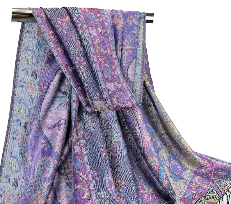 May include: A purple and blue paisley patterned scarf with gold accents. The scarf is folded and draped over a metal rod.