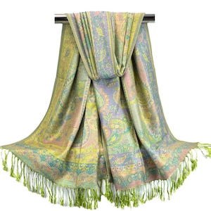 May include: A pastel-colored scarf with a paisley pattern and fringe. The scarf is draped over a metal bar, showcasing its intricate design. The color palette includes shades of yellow, pink, and blue, creating a soft and elegant look. The scarf's fringe adds a touch of texture.