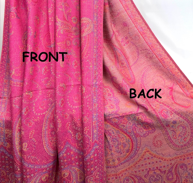 May include: A bright pink shawl featuring an intricate woven paisley pattern in shades of gold and purple. The image displays both sides of the fabric, labeled with the text FRONT on the left and BACK on the right, showing the color variation.