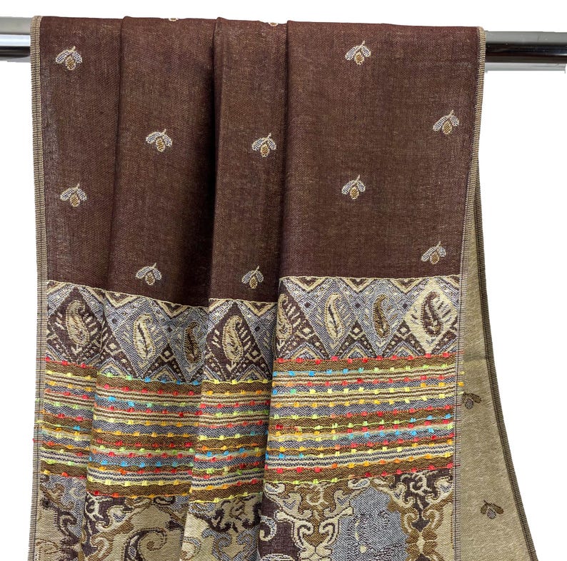 K&ouml;nnte beinhalten: Ein brauner Schal mit detailliertem Rand. Der Schal hat ein sich wiederholendes Muster aus kleinen, gestickten bienenartigen Formen. Der Rand weist Paisley- und geometrische Designs mit farbenfrohen Akzenten auf. Der Schal besteht aus einem weichen, gewebten Material.