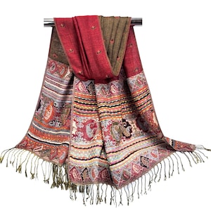 K&ouml;nnte beinhalten: Ein farbenfroher Schal mit Paisley-Muster und Fransen. Der Schal hat ein rotes und braunes Farbschema mit aufwendigen Designs in Orange, Blau und Wei&szlig;. Der Schal ist aus einem weichen Material gefertigt und eignet sich perfekt, um jedem Outfit einen Hauch von Eleganz zu verleihen.