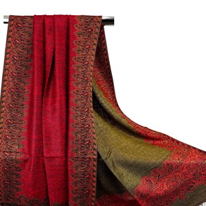 Pode incluir: Um xale vermelho e verde com padr&atilde;o paisley e borda franjada. O xale est&aacute; pendurado em um cabide.