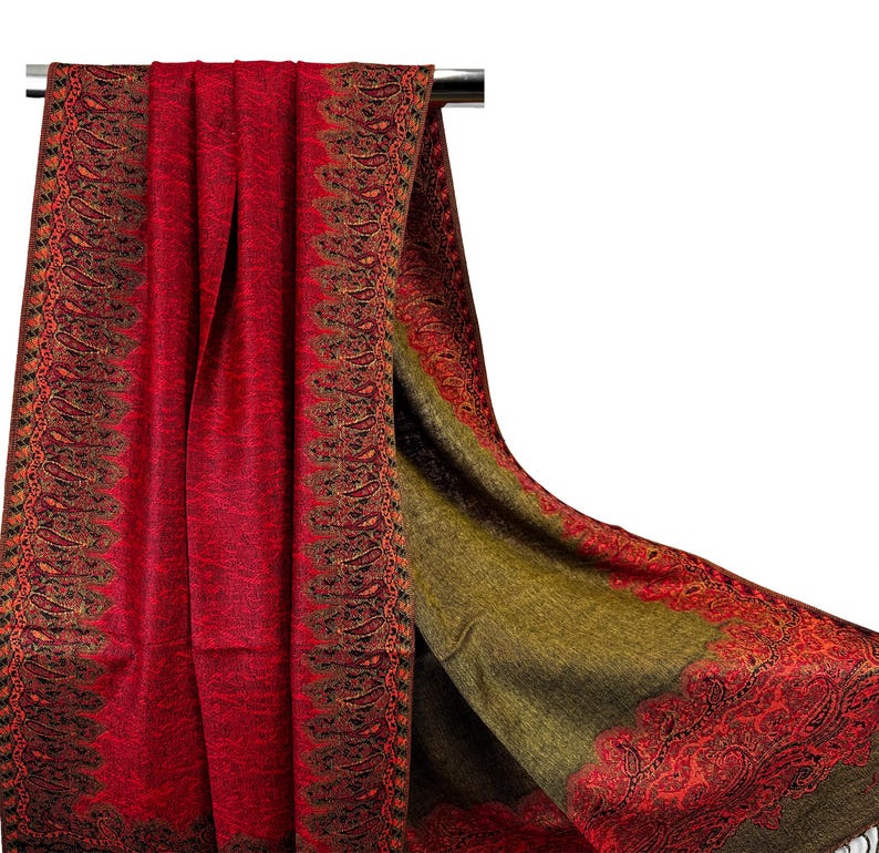 Pode incluir: Um xale vermelho e verde com padr&atilde;o paisley e borda franjada. O xale est&aacute; pendurado em um cabide.