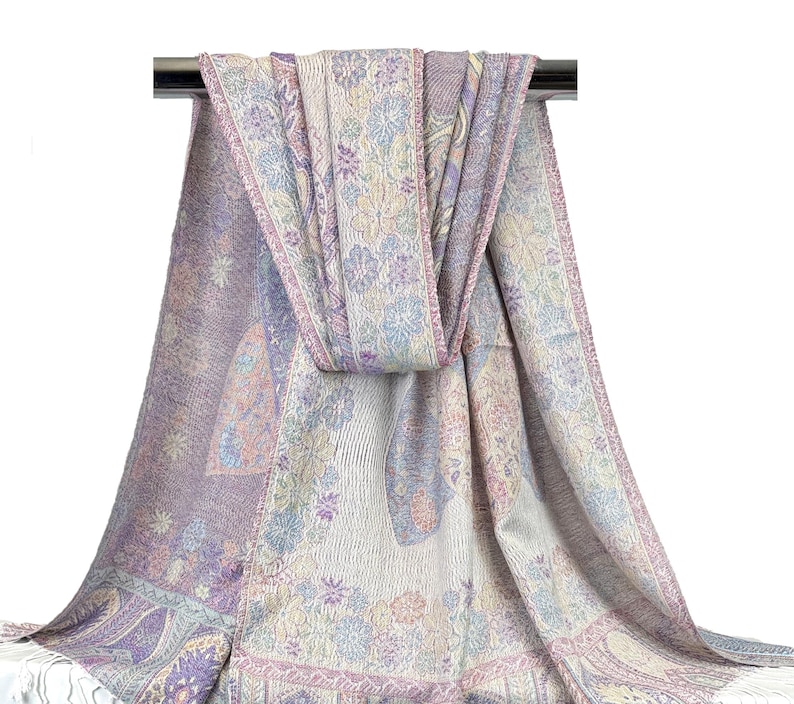 May include: A soft, lightweight scarf with a paisley pattern in shades of purple, pink, and white. The scarf is made of a blend of wool and cashmere and is perfect for adding a touch of elegance to any outfit.