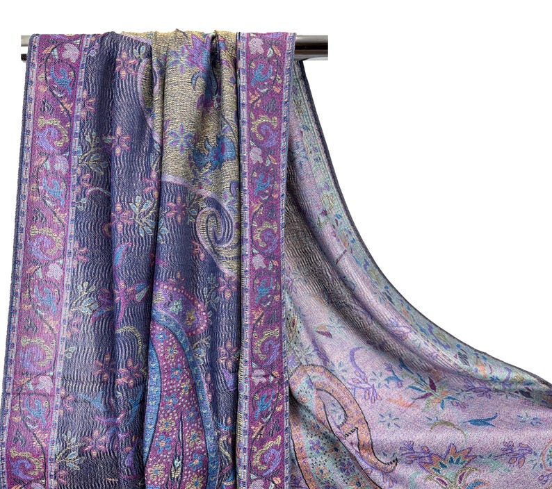 May include: A purple and blue paisley patterned scarf with a fringed edge. The scarf is made of a soft, lightweight fabric and is perfect for adding a touch of elegance to any outfit.