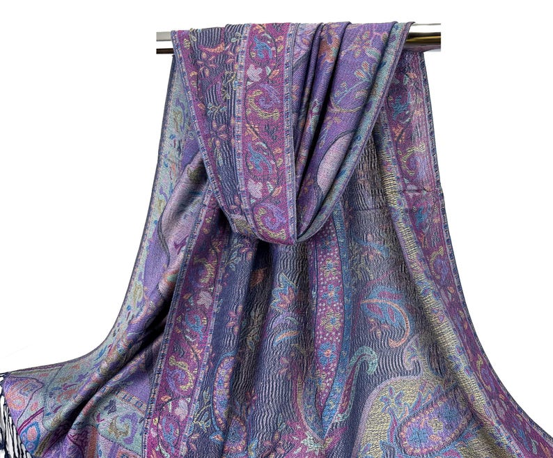 May include: A purple and blue paisley patterned scarf with a fringed edge. The scarf is draped over a silver rod.