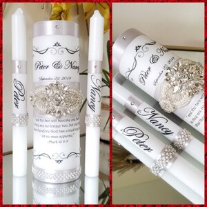 May include: Two white unity candles with silver ribbon and pearl accents. The larger candle has the names "Peter & Nancy" and the date "September 22, 2019" printed on it. The smaller candles have the names "Peter" and "Nancy" printed on them. The larger candle also has a quote from Mark 10:8-9 printed on it.