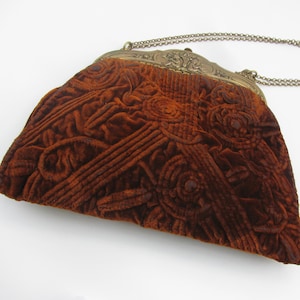 Precioso bolso de terciopelo color tierra quemada de los años 20 con marco dorado grabado con imágenes de música y asa de cadena