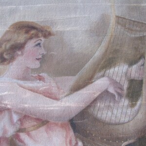 May include: An antique painting depicts a woman with auburn hair playing a harp. She wears a pink dress with a gold sash. The harp is a light brown color, and the background is a neutral beige.