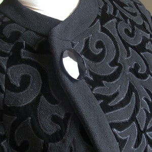 May include: Black velvet jacket with a swirling pattern and a black button.