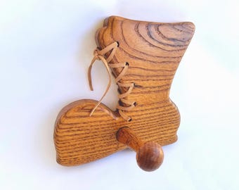 May include: A wooden boot-shaped wall hook with a brown leather lace. The hook is made of light brown wood with a natural wood grain.