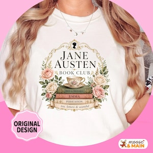 May include: White t-shirt featuring a floral design with the text "JANE AUSTEN BOOK CLUB." The design includes stacked books, a teacup, and the titles "Pride & Prejudice," "Emma," and "Persuasion." The words "tea, letters & scandal" are also present.