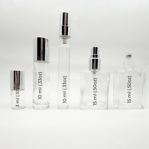 May include: Five clear glass bottles with silver caps and labels indicating their volume in milliliters and ounces. The bottles are arranged in a row from smallest to largest.