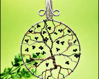 May include: A silver wire tree of life pendant with black beads. The pendant is circular and has a silver bail.