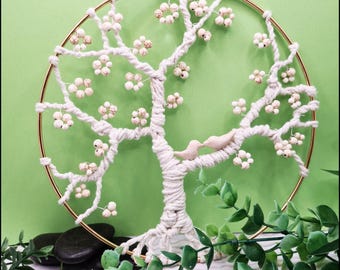 May include: A white macrame tree wall hanging with a gold hoop and white beads. Two small white birds are perched on a branch.