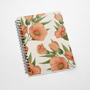 May include: A spiral bound notebook with a floral design. The cover features a repeating pattern of peach-colored hibiscus flowers with green leaves on a cream background.