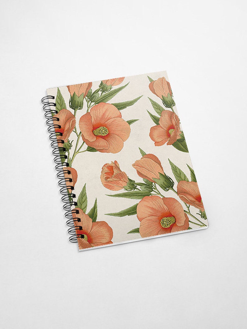 May include: A spiral bound notebook with a floral design. The cover features a repeating pattern of peach-colored hibiscus flowers with green leaves on a cream background.