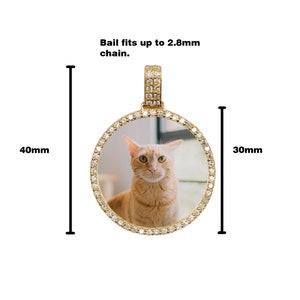 May include: Gold-tone round photo locket pendant with a clear glass insert and a diamond-like crystal border. The locket is 40mm in height and 30mm in width. The bail fits up to a 2.8mm chain.