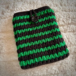 May include: A black and green striped crocheted phone case with a black button closure.