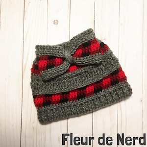 May include: Gray and red plaid crochet hat with a bow on top. The hat is made with a soft yarn and has a comfortable fit.