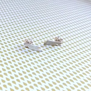 May include: A pair of silver earrings with a geometric lightning bolt design.
