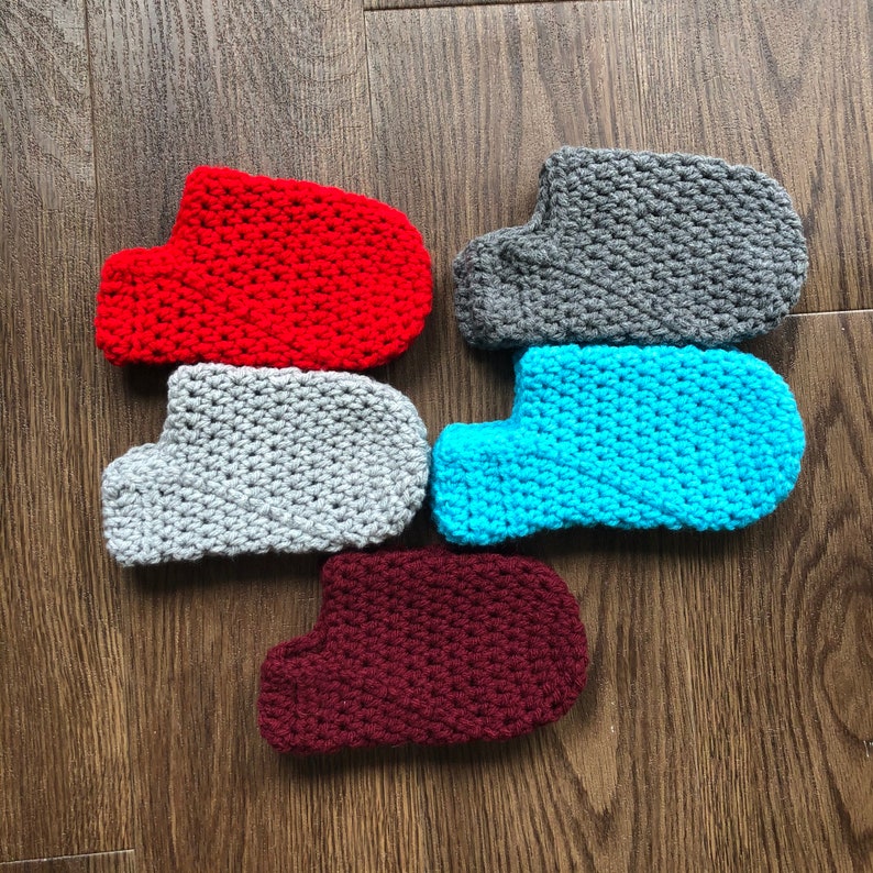 May include: Five crocheted slipper socks in different colors: red, gray, blue, maroon, and gray. The socks are all made with a similar stitch pattern.