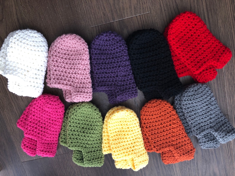 May include: A set of 10 crocheted fingerless gloves in various colors, including white, pink, purple, black, red, gray, green, yellow, and orange. The gloves are all made with a similar stitch pattern and are laid out in a row on a wooden surface.