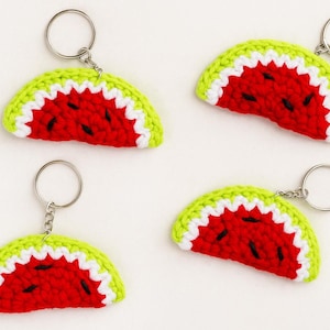 May include: Four handmade crochet watermelon slice keychains. Each keychain features a red center with black seed details, a white rind, and a green outer edge. The keychains have silver-colored metal rings.