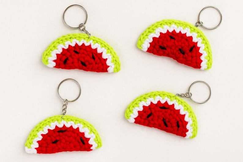 May include: Four handmade crochet watermelon slice keychains. Each keychain features a red center with black seed details, a white rind, and a green outer edge. The keychains have silver-colored metal rings.