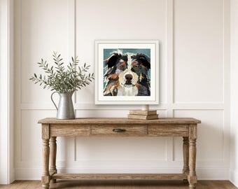 May include: A framed square art print featuring a stylized collage illustration of an Australian Shepherd dog with black, white, and brown fur tones against a muted teal background, displayed in a white frame on a wall.