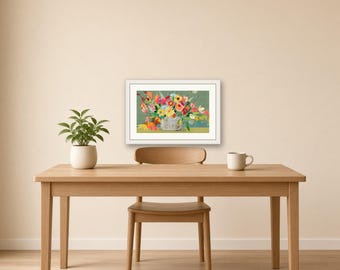 May include: A framed horizontal art print featuring a colorful floral arrangement in a vase against a muted green background. The artwork is displayed on a wall above a wooden table with a small potted plant and a white ceramic mug.