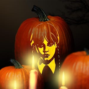 Könnte beinhalten: Ein geschnitzter orangefarbener Kürbis mit einem Porträt einer Person mit geflochtenen Zöpfen und einem Hemd mit Kragen. Das Gesicht wird von innen beleuchtet, mit zwei kleineren Kürbissen und brennenden Kerzen im Vordergrund.