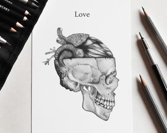 May include: A black and white graphite drawing on paper featuring a human skull with an anatomical heart emerging from the top. The word Love is printed above the skull. Several drawing pencils are positioned around the artwork.