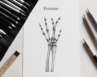 May include: A white sheet of paper featuring a detailed black and white pencil drawing of a human skeleton hand and forearm bones. The word Fortune is printed in black text above the illustration, surrounded by various drawing pencils.