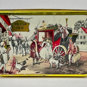 May include: A vintage tin box with a colorful illustration of a horse-drawn carriage arriving at a quaint inn. The sign above the inn reads "Ye Old Inn".