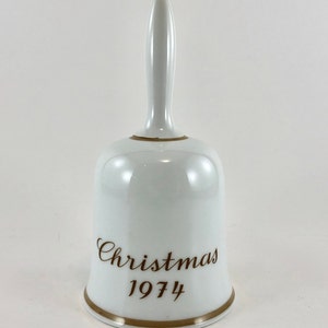 May include: White porcelain Christmas bell with a gold trim and the words "Christmas 1974" in brown lettering.
